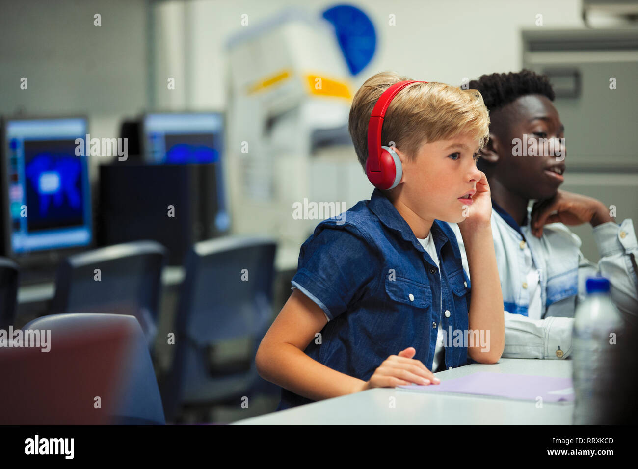 Focalizzato junior high school boy con cuffie in aula Foto Stock