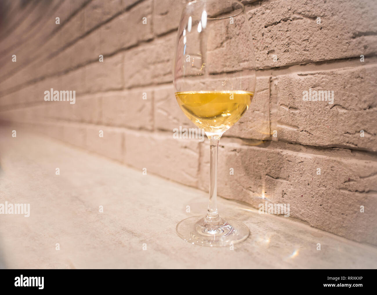Un bicchiere di vino bianco vicino a un muro di mattoni Foto Stock