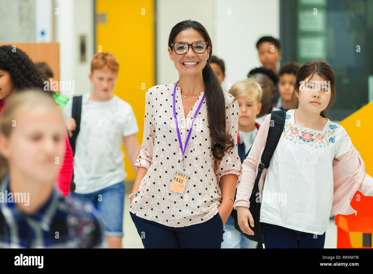 Junior alta gli studenti a piedi attorno a sorridente insegnante femmina Foto Stock