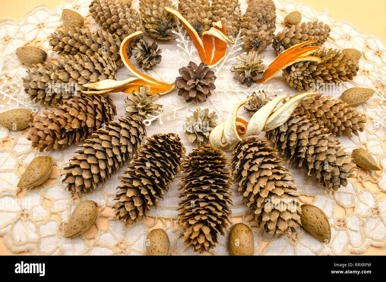 Decorazione di natale su un tovagliolo ricamato da una varietà di coni, essiccato a buccia d'arancia, mandorle e fiocchi di neve su sfondo giallo Foto Stock