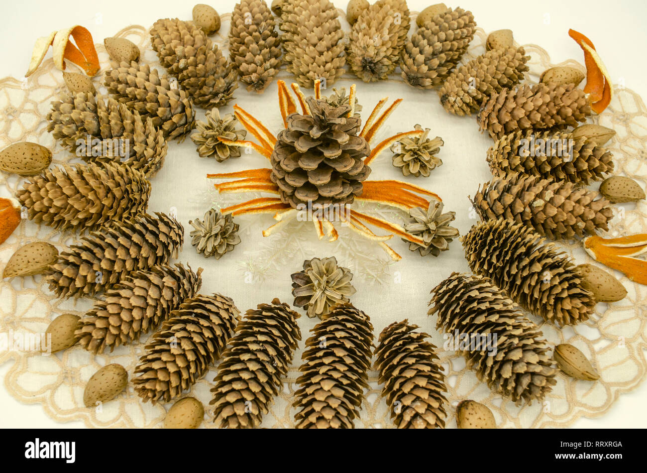 Ricamato tovagliolo bianco coperto con un telaio di forma ovale con un pattern di coni di diverse razze, fiocchi di neve, scorza di arancia e mandorle sui bordi su un Foto Stock