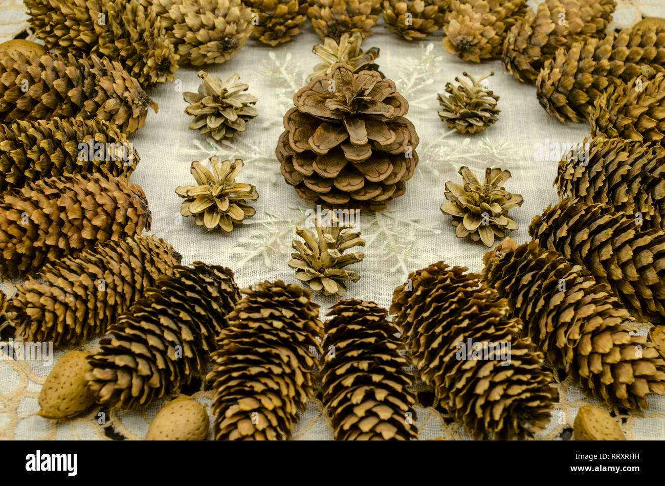 Bianco ricamato tovagliolo ondulata con un pattern di coni di diverse razze, fiocchi di neve e mandorle lungo i bordi della configurazione su uno sfondo nero Foto Stock