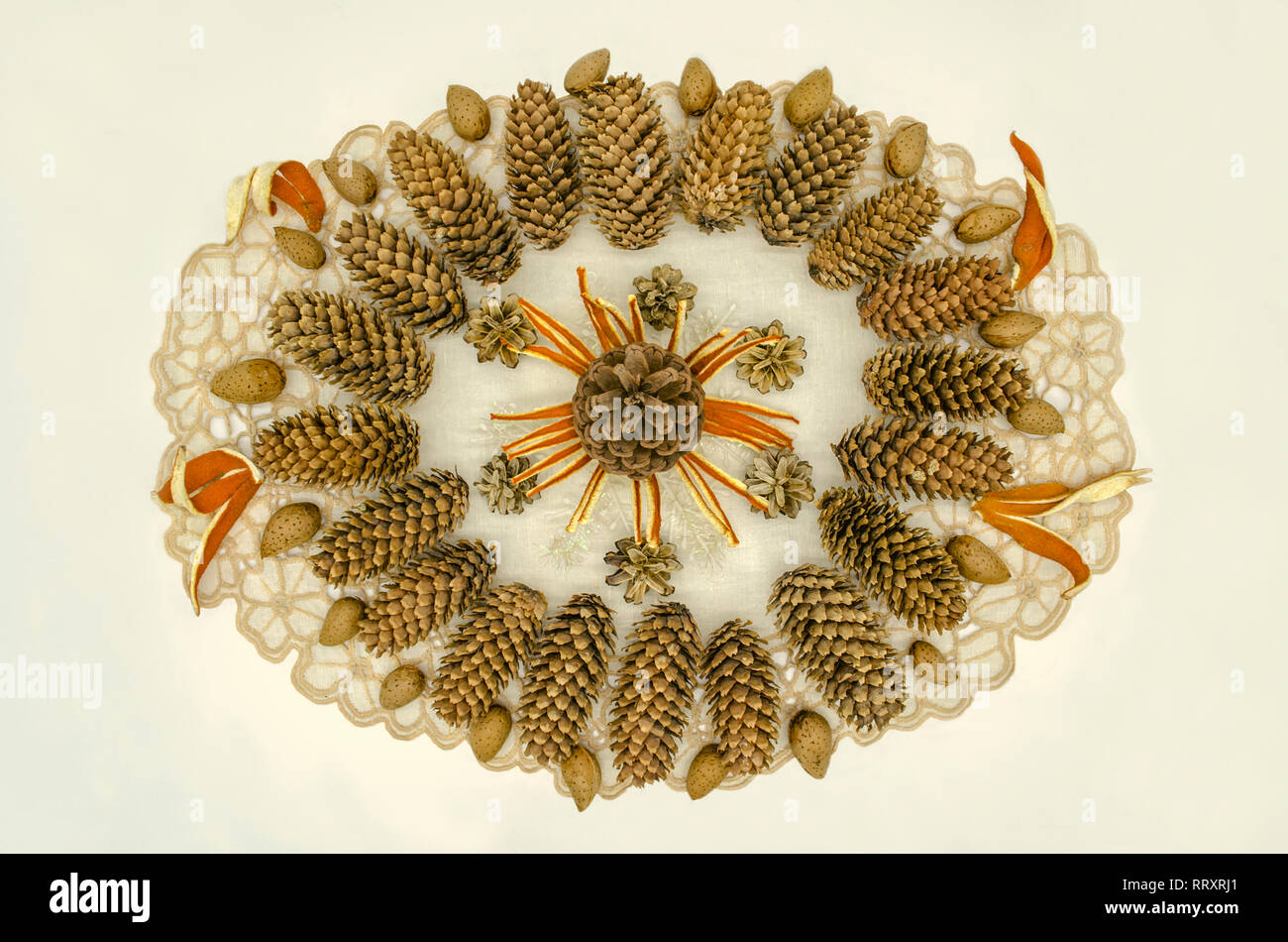 Sfondo bianco con tovagliolo ricamato coperto con cornice ovale con pattern di coni di diverse razze, fiocchi di neve, scorza di arancia e le mandorle sulla Foto Stock