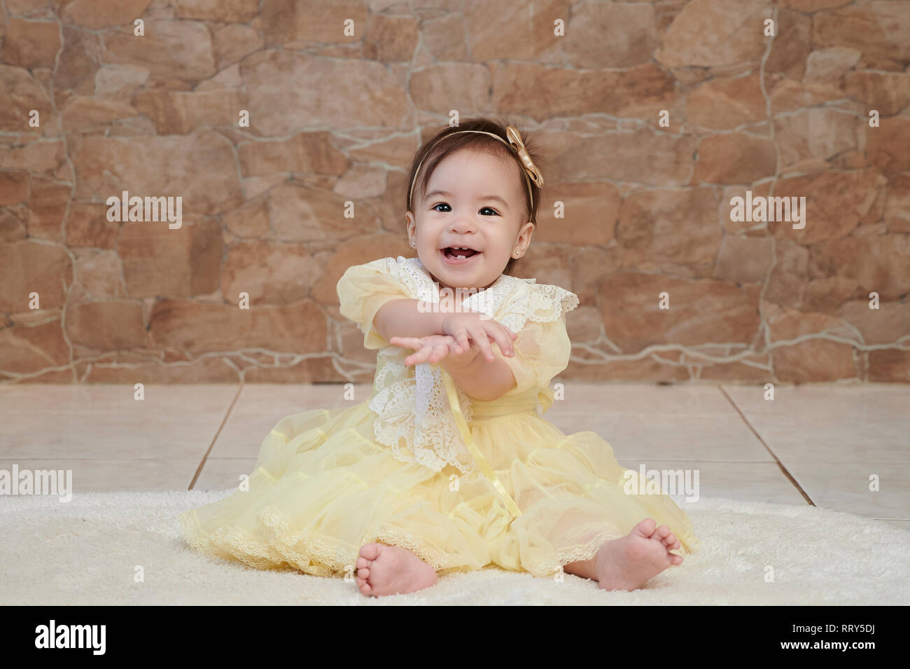 Una bambina in abito giallo sorridente e battendo le mani Foto Stock