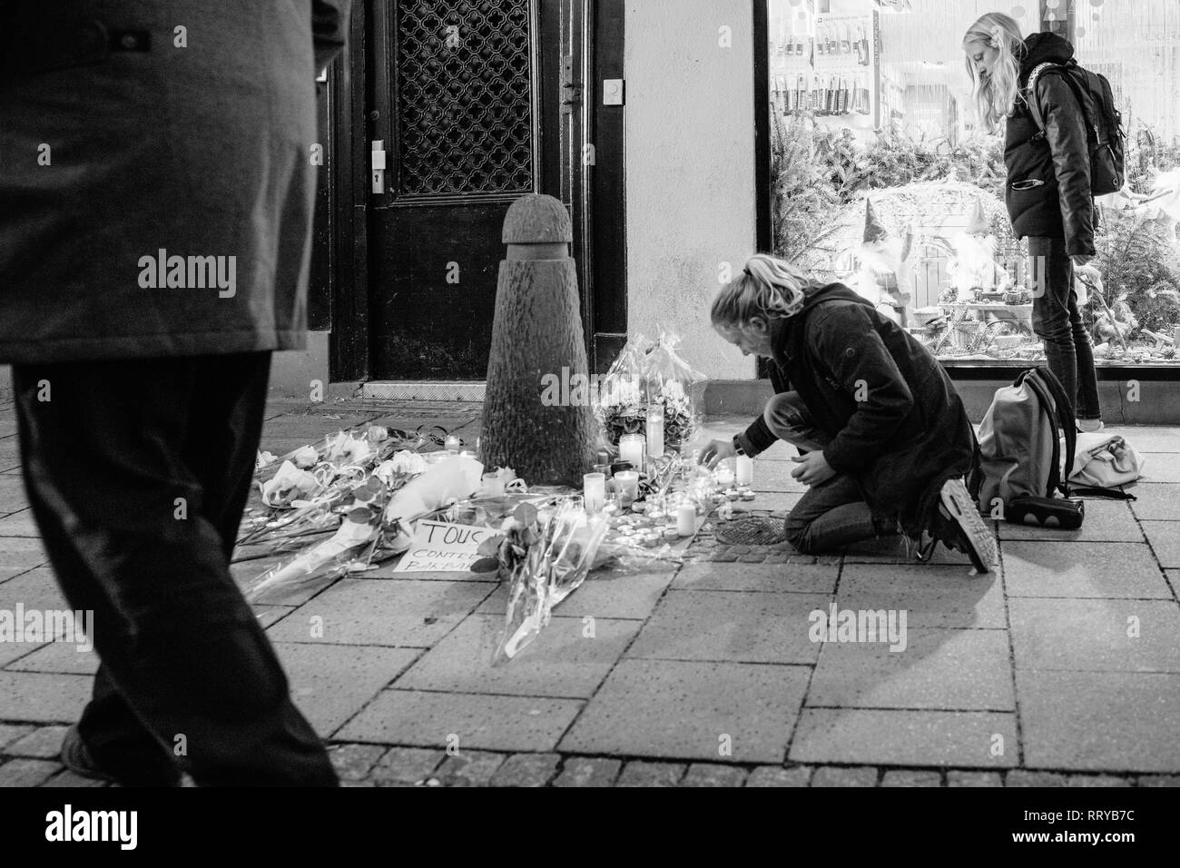 Strasburgo, Francia - Dic 13, 2018: giovani ragazze accendendo candele su Rue des Orfevres a partecipare a una veglia con più luce di candele fiori e messaggi per le vittime degli attentati Cherif Chekatt al mercatino di Natale Foto Stock