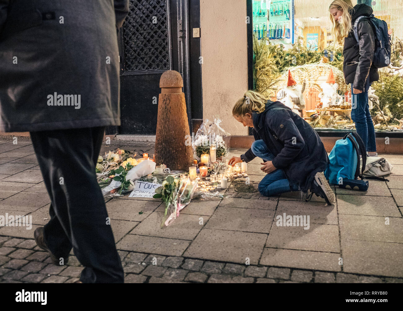 Strasburgo, Francia - Dic 13, 2018: giovani ragazze accendendo candele su Rue des Orfevres a partecipare a una veglia con più luce di candele fiori e messaggi per le vittime degli attentati Cherif Chekatt al mercatino di Natale Foto Stock