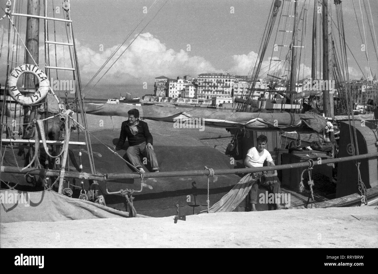 Griechenland, Grecia - Zwei junge Männer an Bord ihres Segelboots im Hafen von Korfu, Griechenland, 1950er Jahre. Due giovani uomini a bordo della loro barca a vela nel porto di Korfu, Grecia, 1950s. Foto Stock