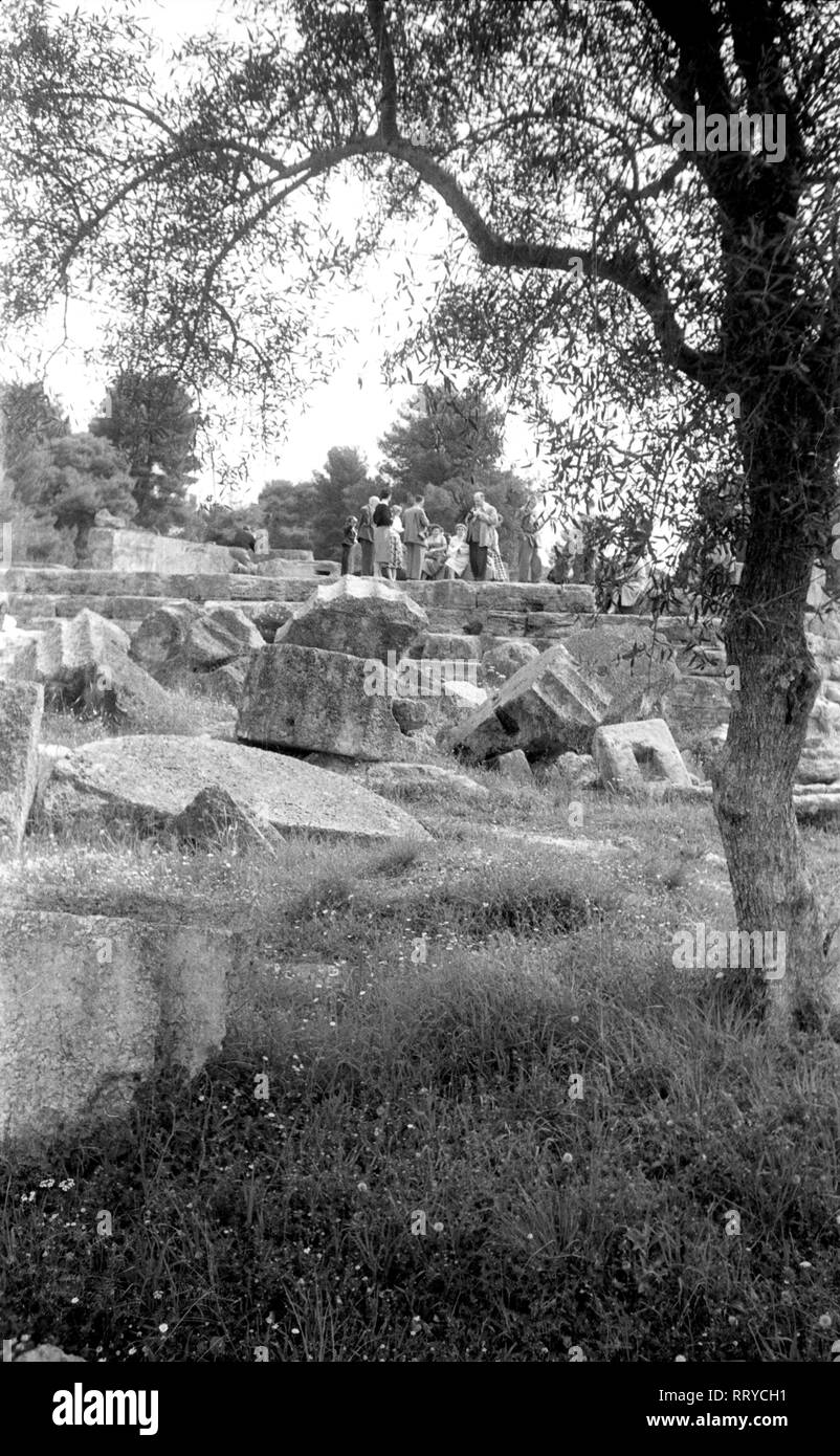 Griechenland, Grecia - Eine Touristengruppe macht eine Rast inmitten der antiken Überreste in Griechenland und hört den Ausführungen des Reiseleiters zu, 1950er Jahre. Un gruppo di turisti in appoggio al centro di un sito archeologico e ascoltando il loro tour guida, Grecia, 1950s. Foto Stock