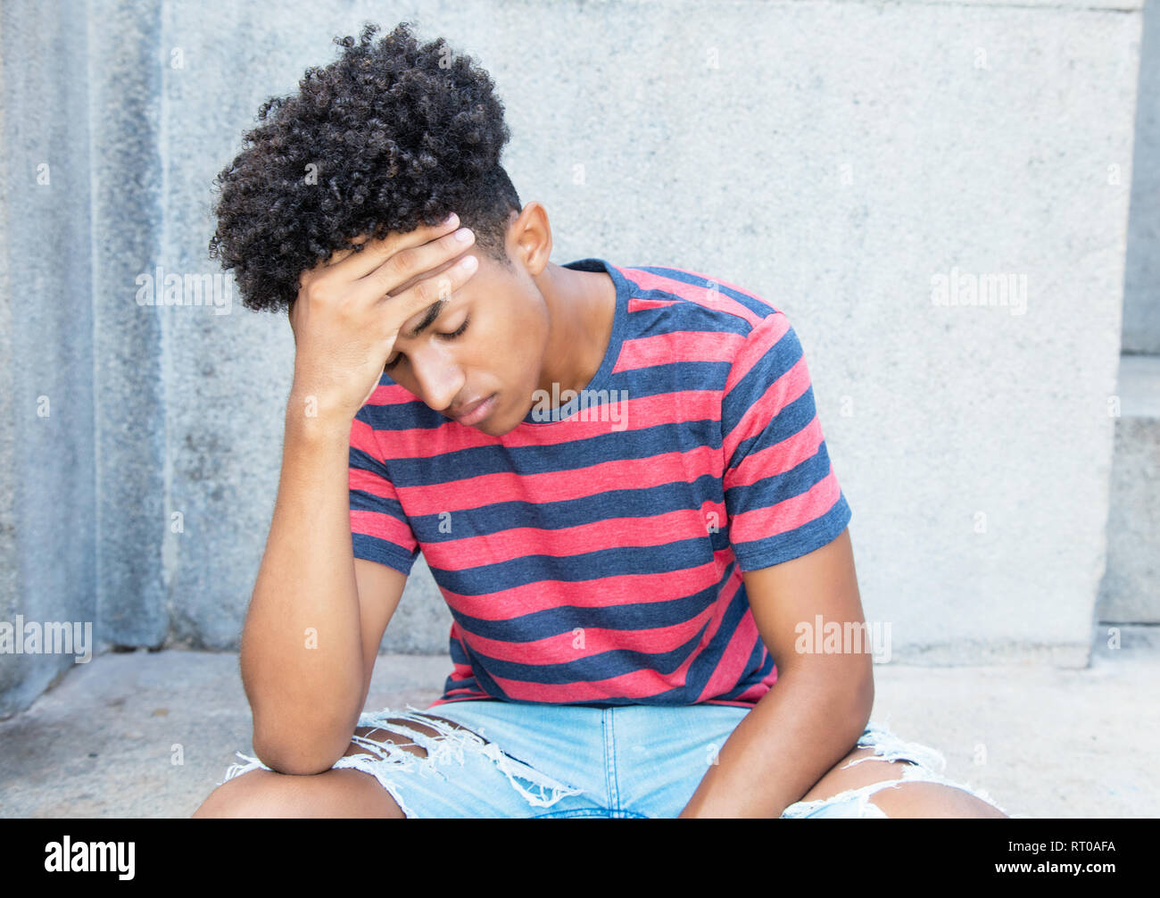 Triste e poveri americano africano giovane adulto uomo all'aperto in estate Foto Stock
