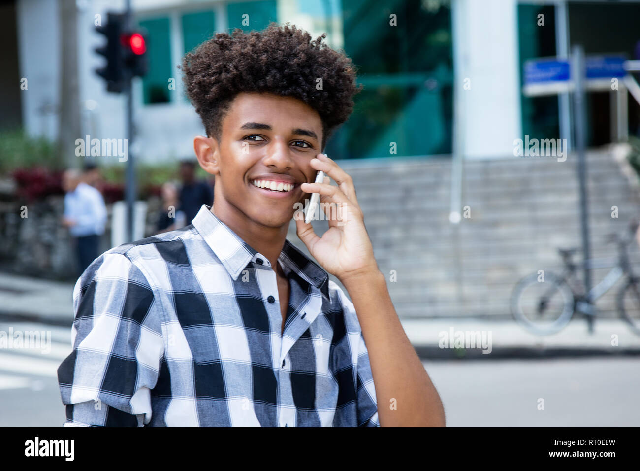 Ridendo americano africano giovane adulto al telefono cellulare all'aperto in città Foto Stock