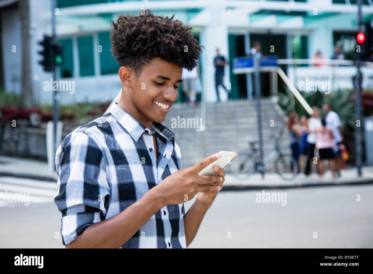 African American giovane adulto inviando un messaggio con il telefono cellulare all'aperto in città Foto Stock