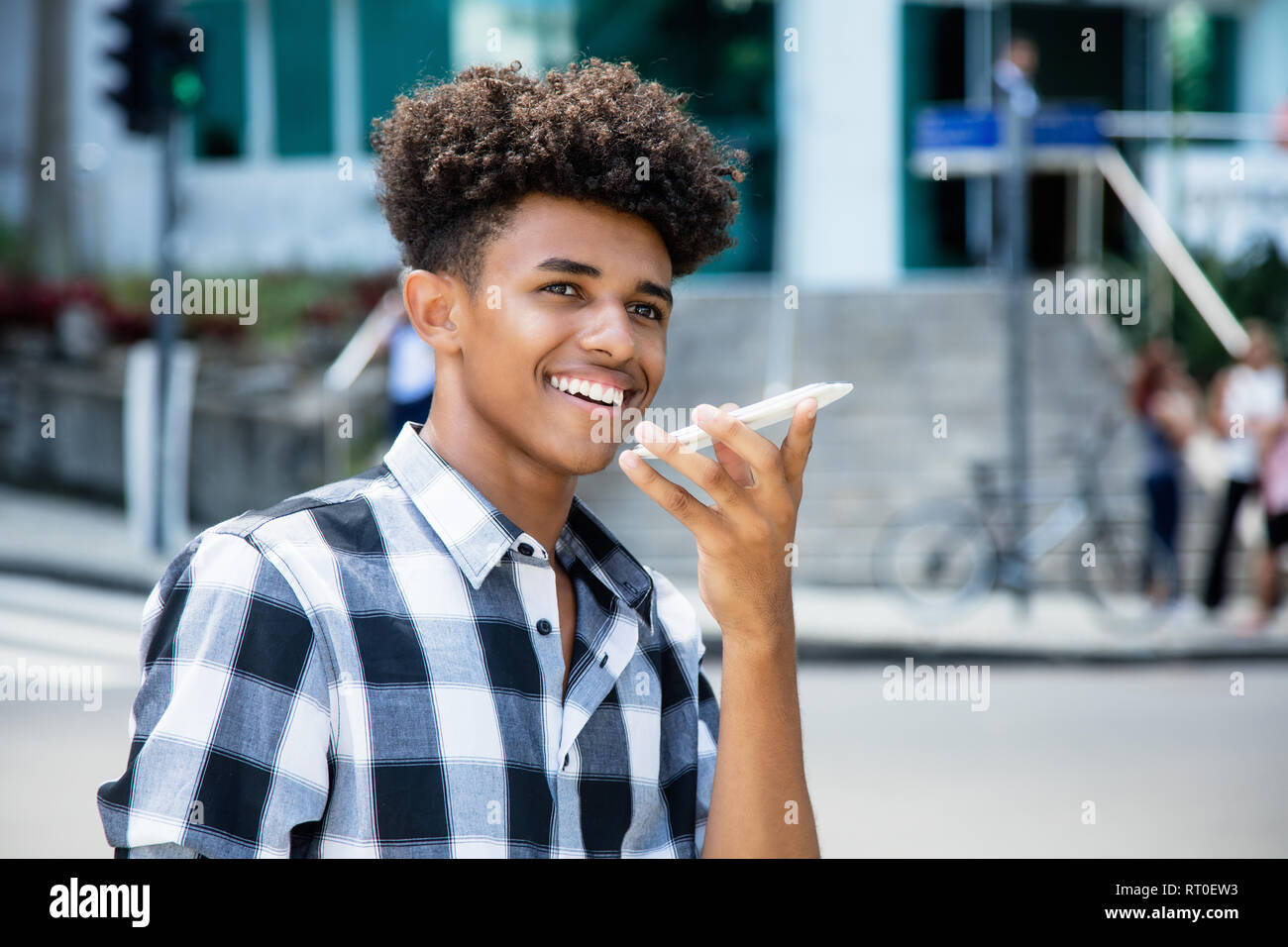 African American giovane adulto utilizzando il riconoscimento vocale al telefono all'aperto in città Foto Stock