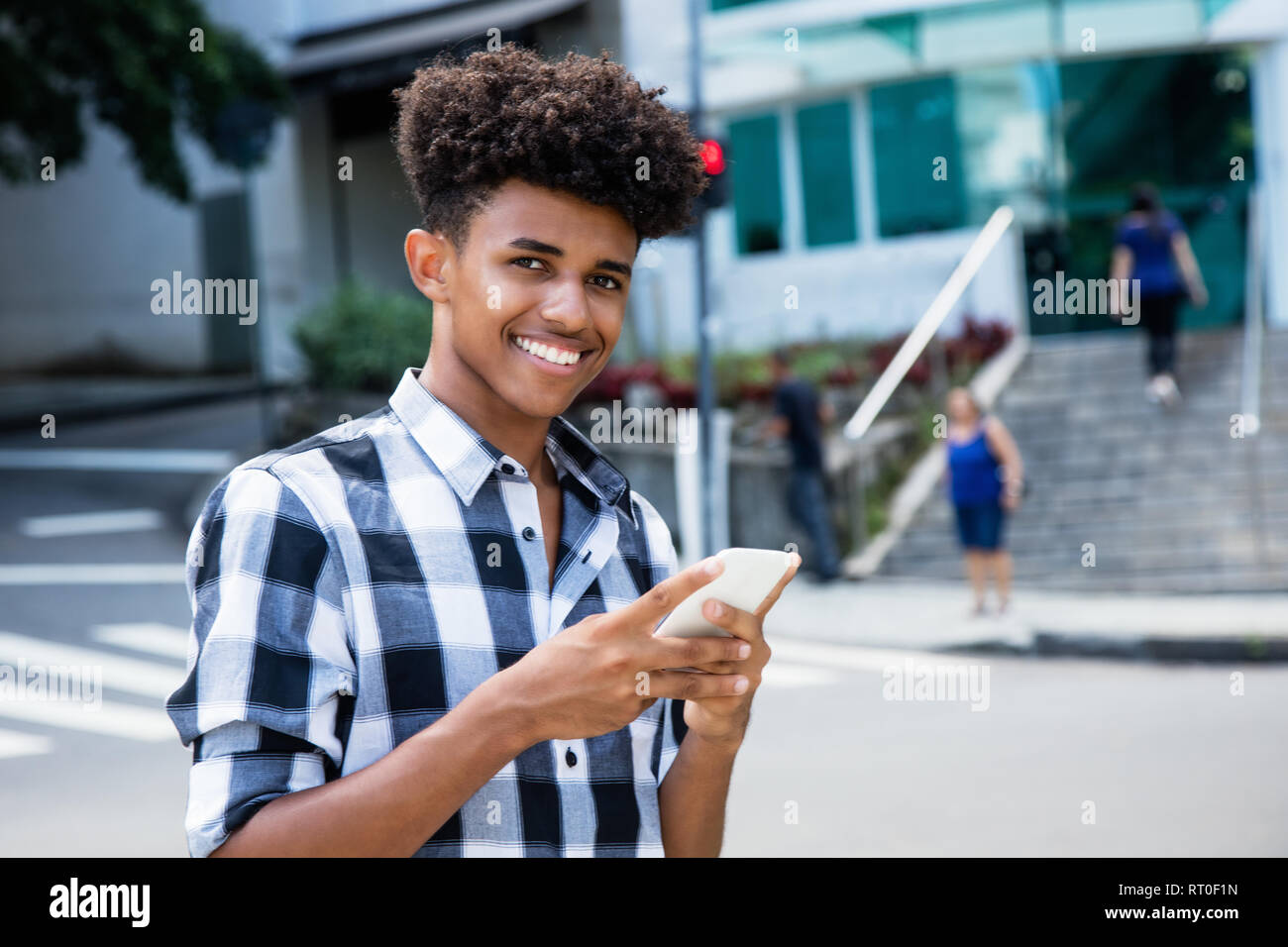 African American giovane adulto utilizzando il telefono cellulare per internet outdoor in città Foto Stock