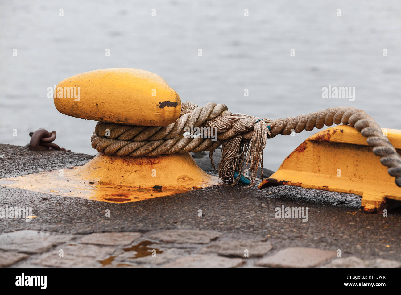 Bollard giallo con funi montate nel molo di cemento. Navi attrezzature di ormeggio Foto Stock