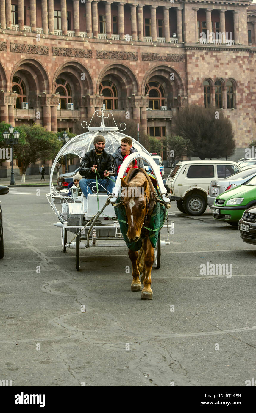 Yerevan,Armenia,Dicembre 03,2018:un originale bianco carrello trainato da un rosso con macchie bianche circus cavallo trasporta persone con bambini intorno alla principale Foto Stock