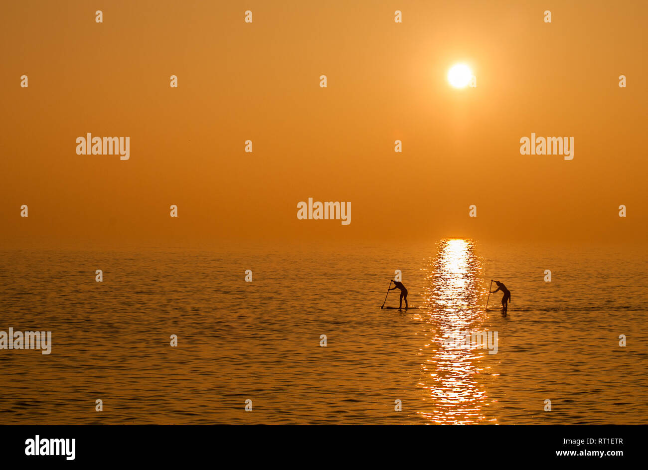 Birling Gap, Eastbourne, East Sussex, Regno Unito..27 febbraio 2019.. Avvicinarsi al tramonto dopo un'altra gloriosa giornata primaverile sulla costa meridionale. Paddleboarders sul mare calmo mentre la nebbia si muove nell'addolcire la scena. . Foto Stock