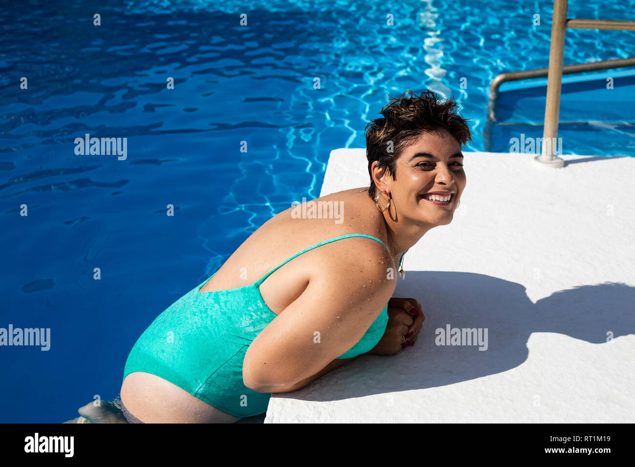Ritratto di plump giovane donna appoggiata sul bordo della piscina Foto Stock