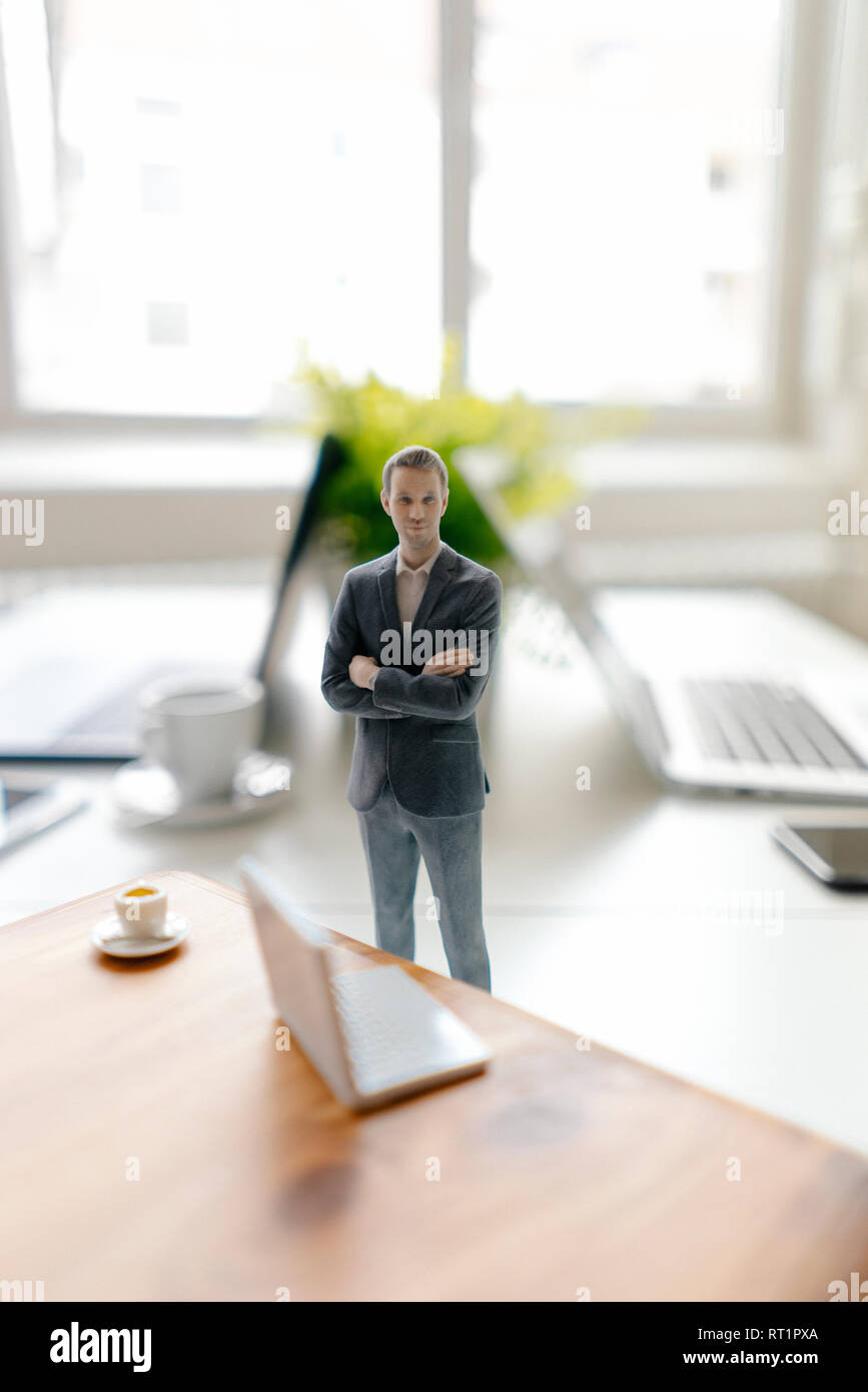 Imprenditore figurina in piedi su una scrivania con i dispositivi mobili e una tazza di caffè Foto Stock