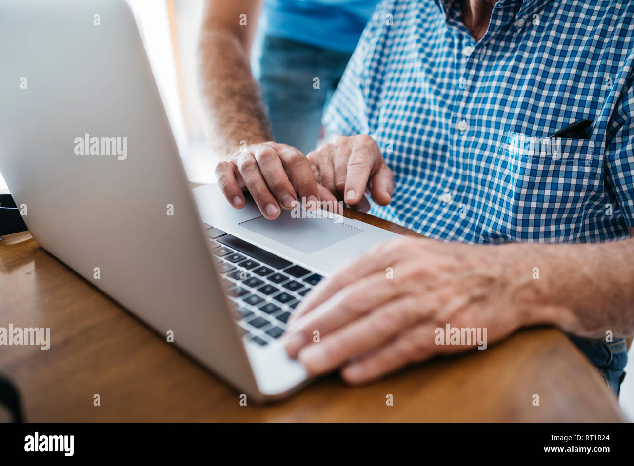 Nipote di adulti insegnamento a suo nonno per uso portatile, close-up Foto Stock