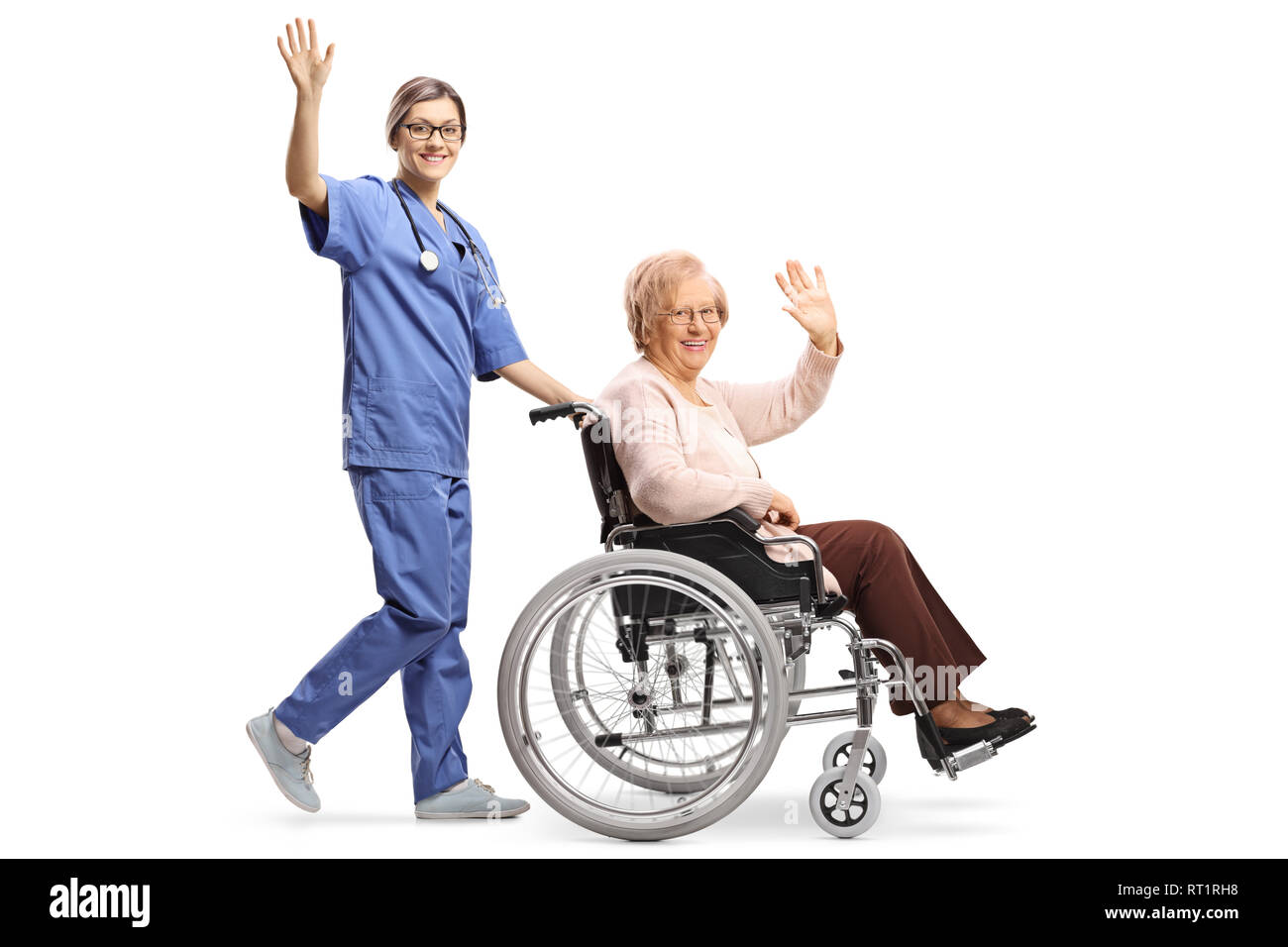 Lunghezza piena ripresa di profilo di una giovane donna infermiera spingendo un senior donna in una sedia a rotelle e agitando isolati su sfondo bianco Foto Stock