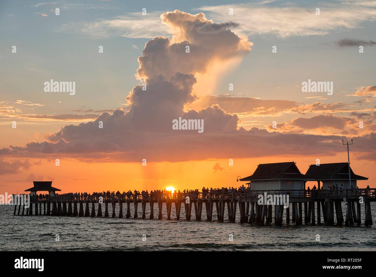 Stati Uniti d'America, Florida, Napoli, sagome di Napoli Molo e turisti con un enorme nube sopra durante il tramonto Foto Stock
