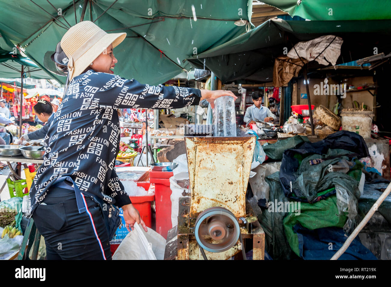 Una signora cambogiana usa un frantoio di ghiaccio nel mercato centrale Phnom Penh Cambogia. Foto Stock