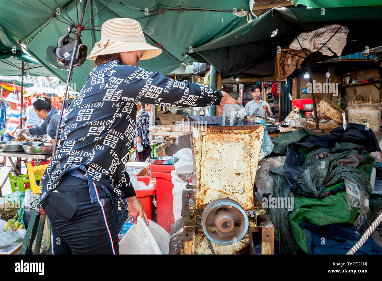 Una signora cambogiana usa un frantoio di ghiaccio nel mercato centrale Phnom Penh Cambogia. Foto Stock