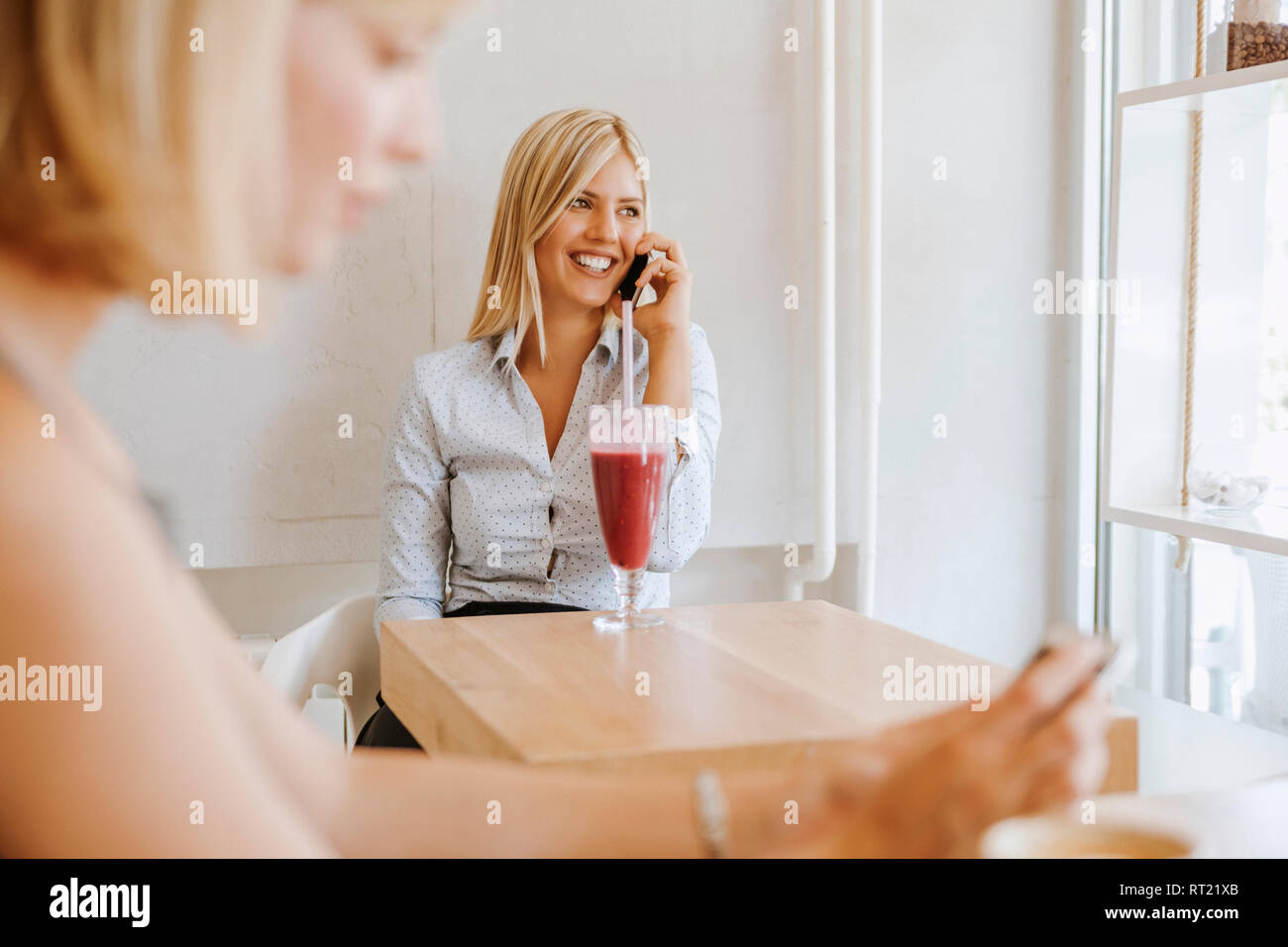 Giovani donne sul telefono cellulare in un cafe Foto Stock