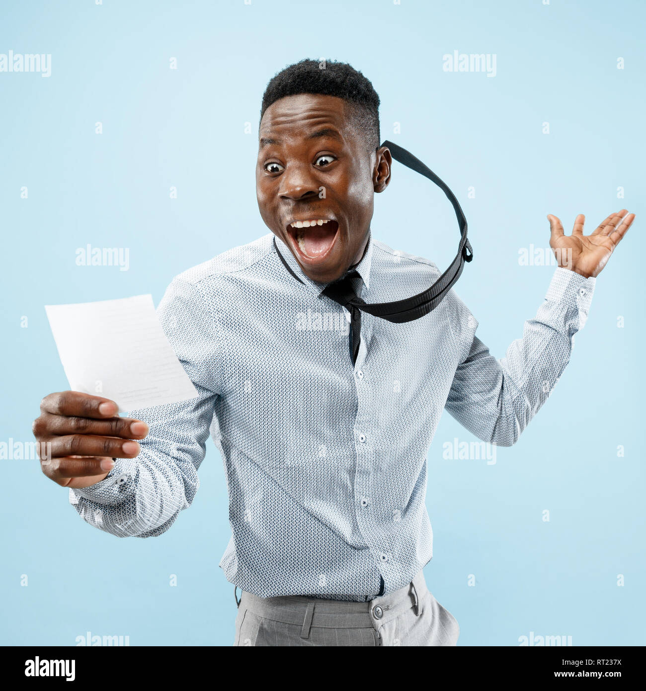 Giovani afro uomo con una sorpresa felice espressione ha vinto una scommessa su blu di sfondo per studio. Viso umano emozioni e concetto di scommesse. Colori alla moda Foto Stock