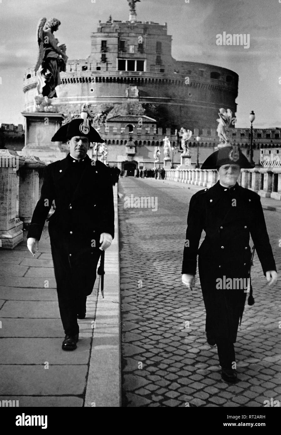 Viaggi a Roma - Italia negli anni cinquanta - Corpo della Gendarmeria dello Stato della Città del Vaticano che attraversano la St Angelo Bridge. Sullo sfondo Castel Sant'Angelo a Roma. Genadrmen auf der Engelsbrücke, im Hintergrund die Engelsburg in Rom, Italien. Data dell'immagine 1954. Foto di Erich Andres Foto Stock