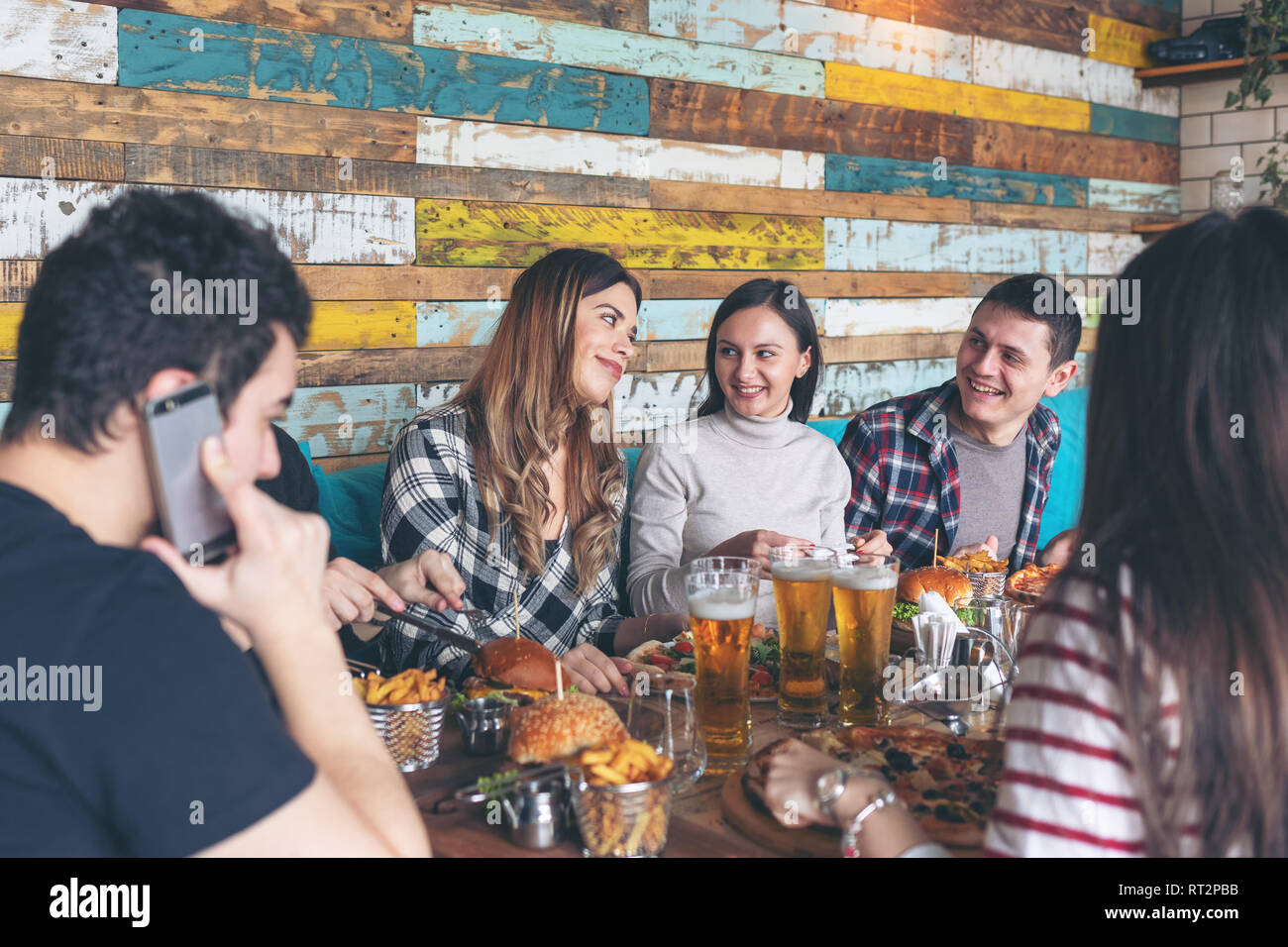 Felice giovani amici celebrando con pizza hamburger e bere birra al pub alla moda Foto Stock