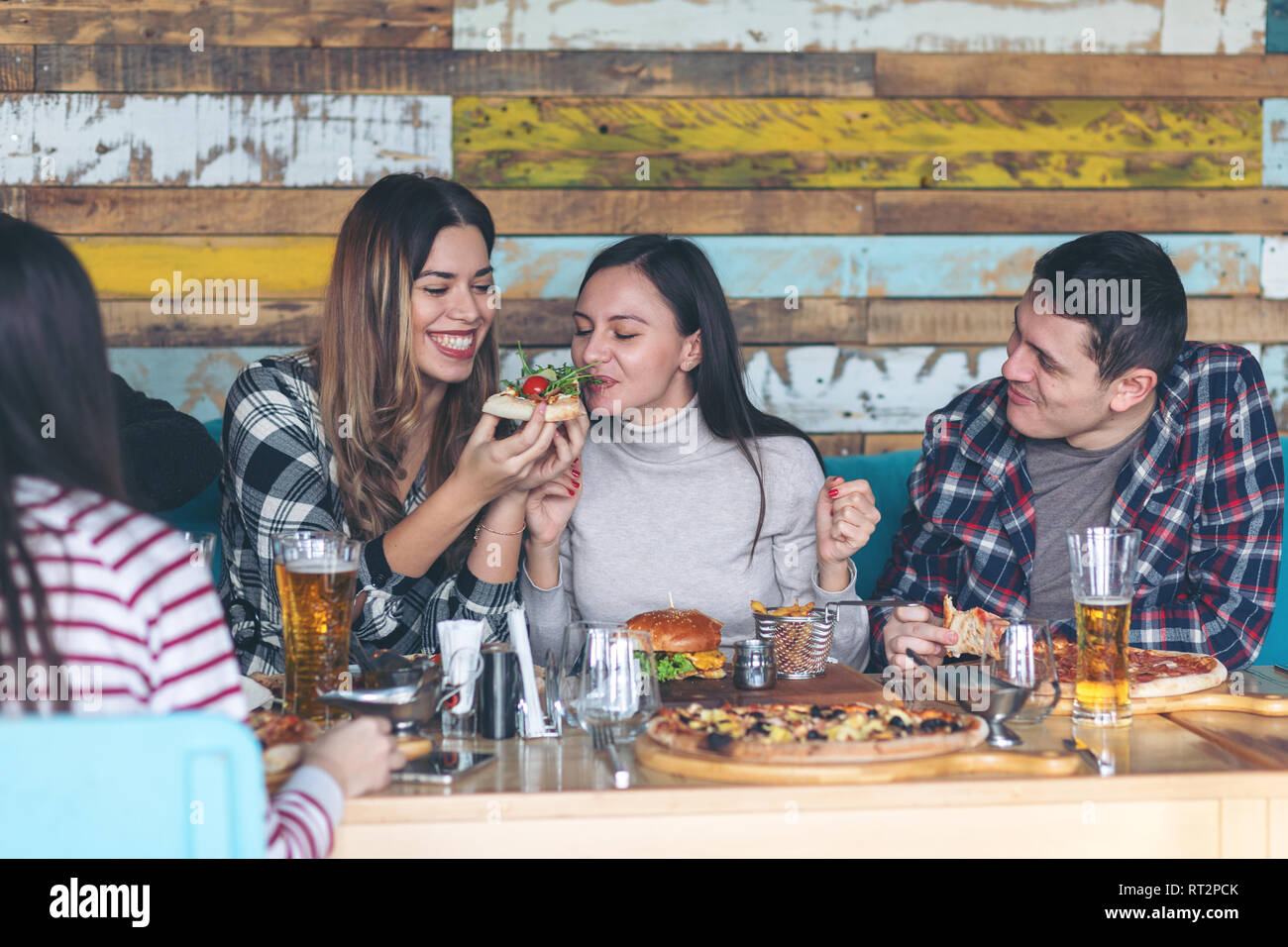 Felice giovani amici celebrando con pizza e birra al pub alla moda Foto Stock
