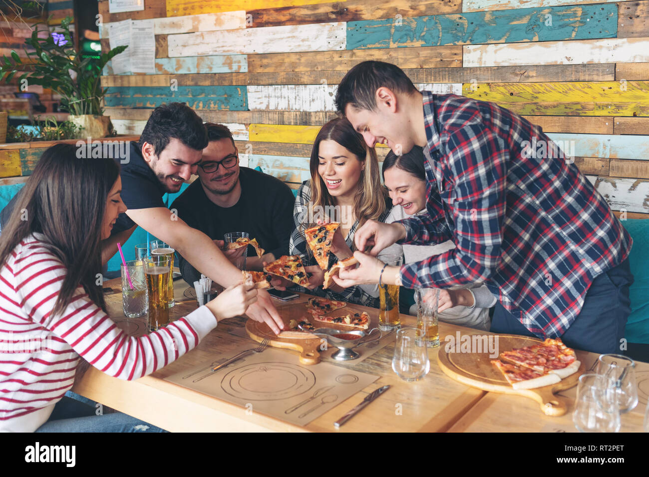 Felice gli amici condividono la pizza al pub rustico Foto Stock