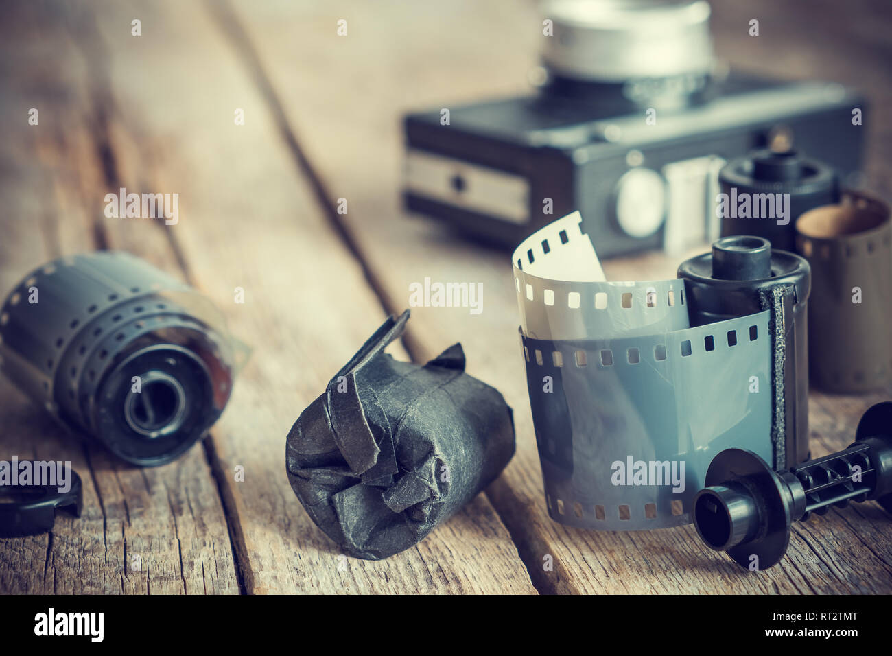 Una vecchia foto rotoli di pellicola e la cassetta su una vecchia scrivania in legno, vintage fotocamera su sfondo. Retrò tonica. Foto Stock