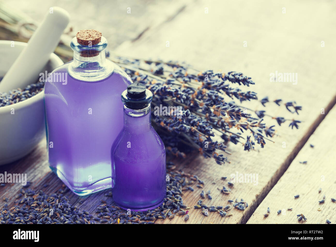 Due bottiglie di olio essenziale, malta e Lavanda fiori mazzetto sul tavolo. Retrò tonica foto. Messa a fuoco selettiva. Foto Stock