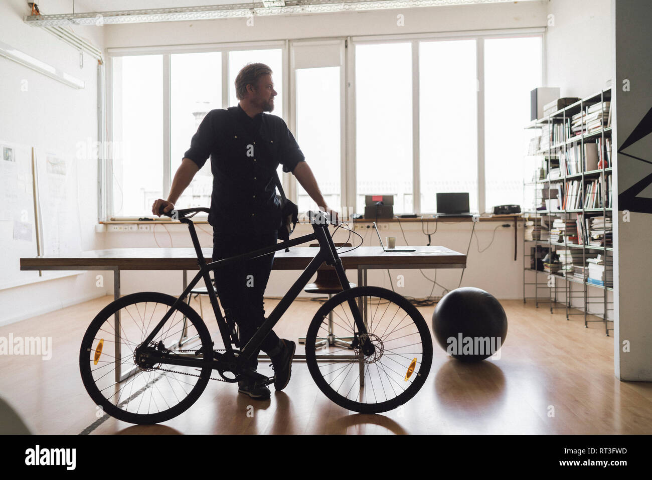 Uomo in ufficio con la sua bicicletta Foto Stock