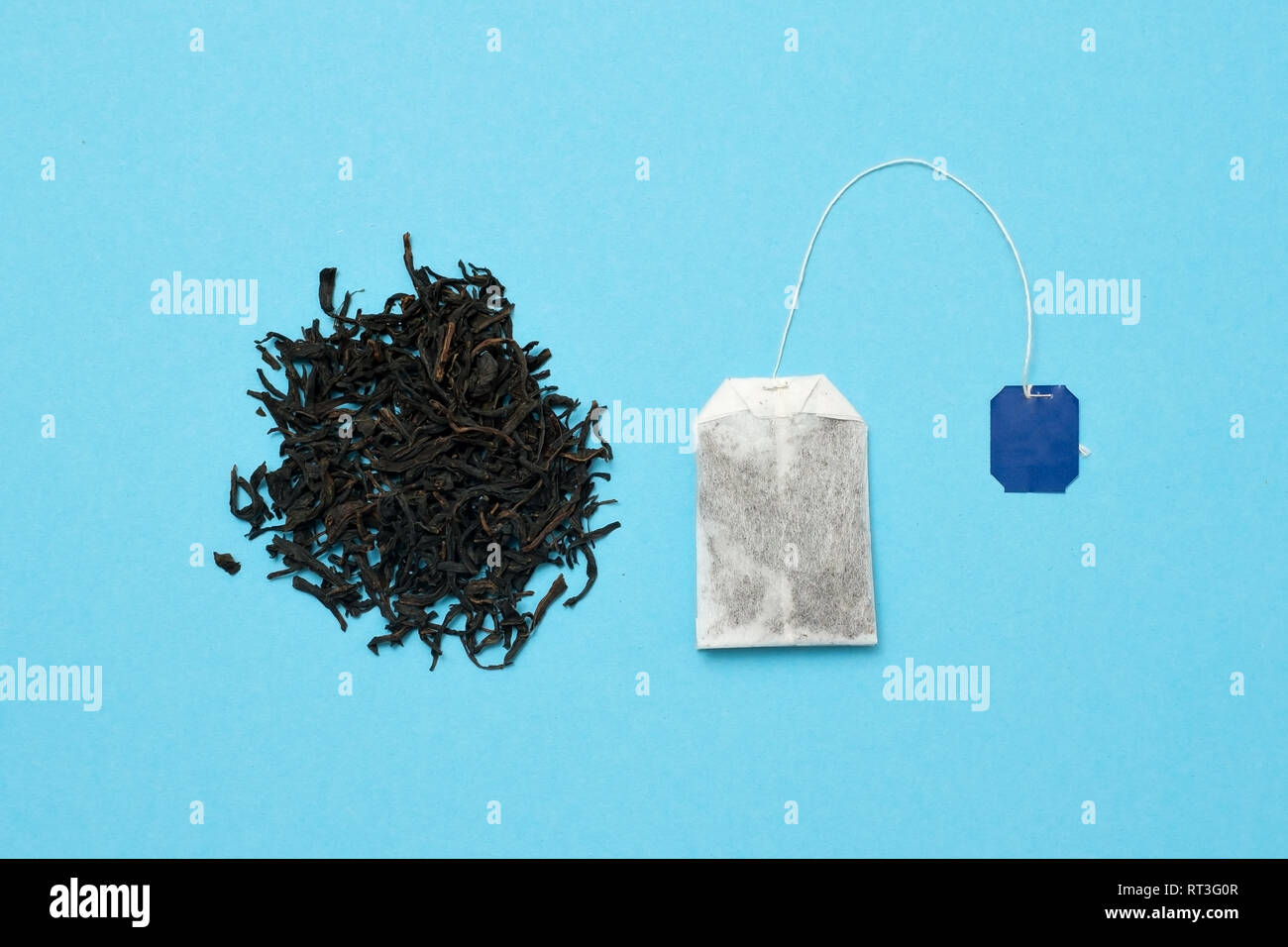 Sacchetto da tè e foglie di colore nero su sfondo blu. Che tipo di tè è meglio scegliere. Vista dall'alto. Foto Stock