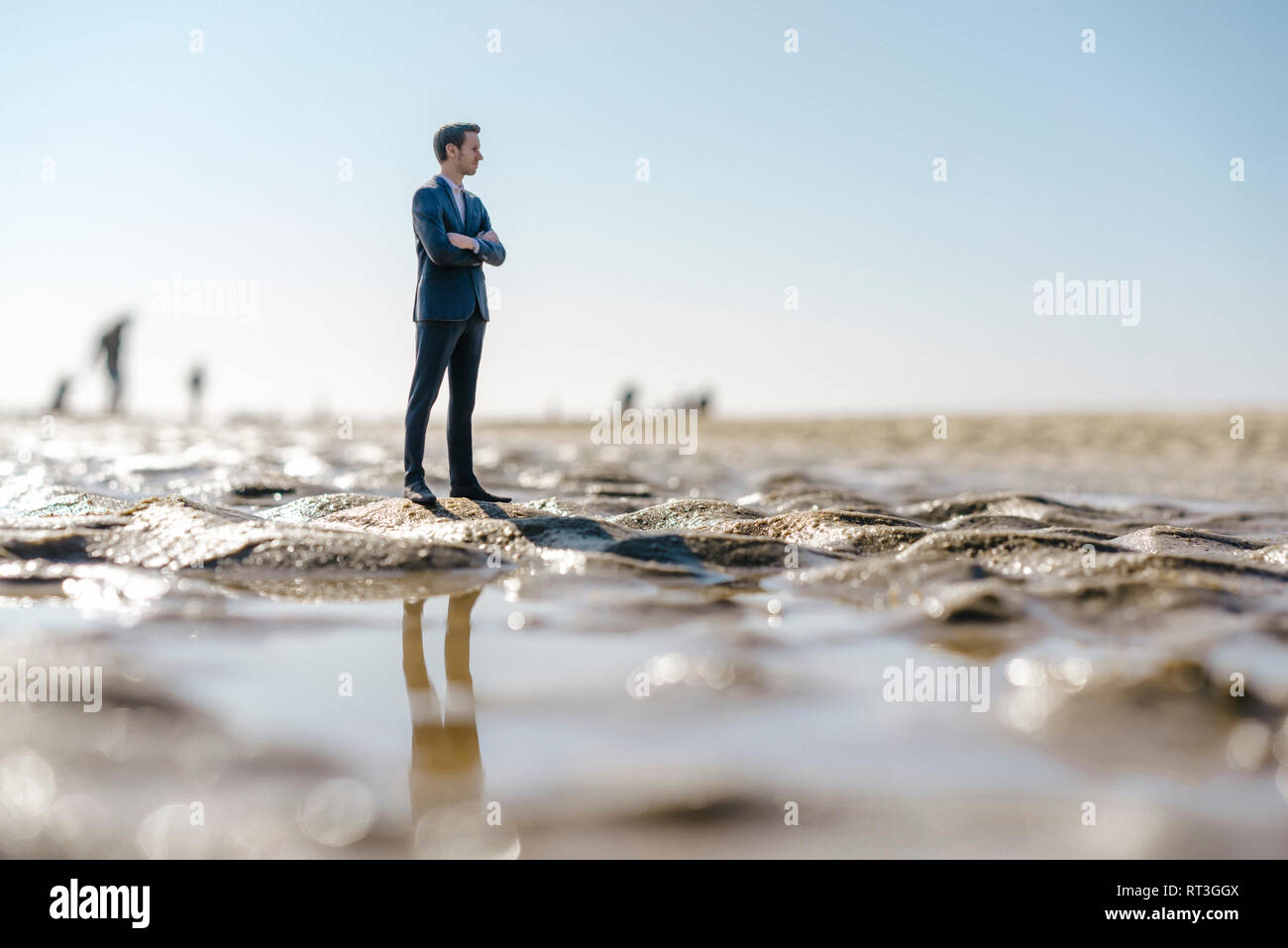 Imprenditore figurina permanente sulla spiaggia bagnata, guardando a distanza Foto Stock