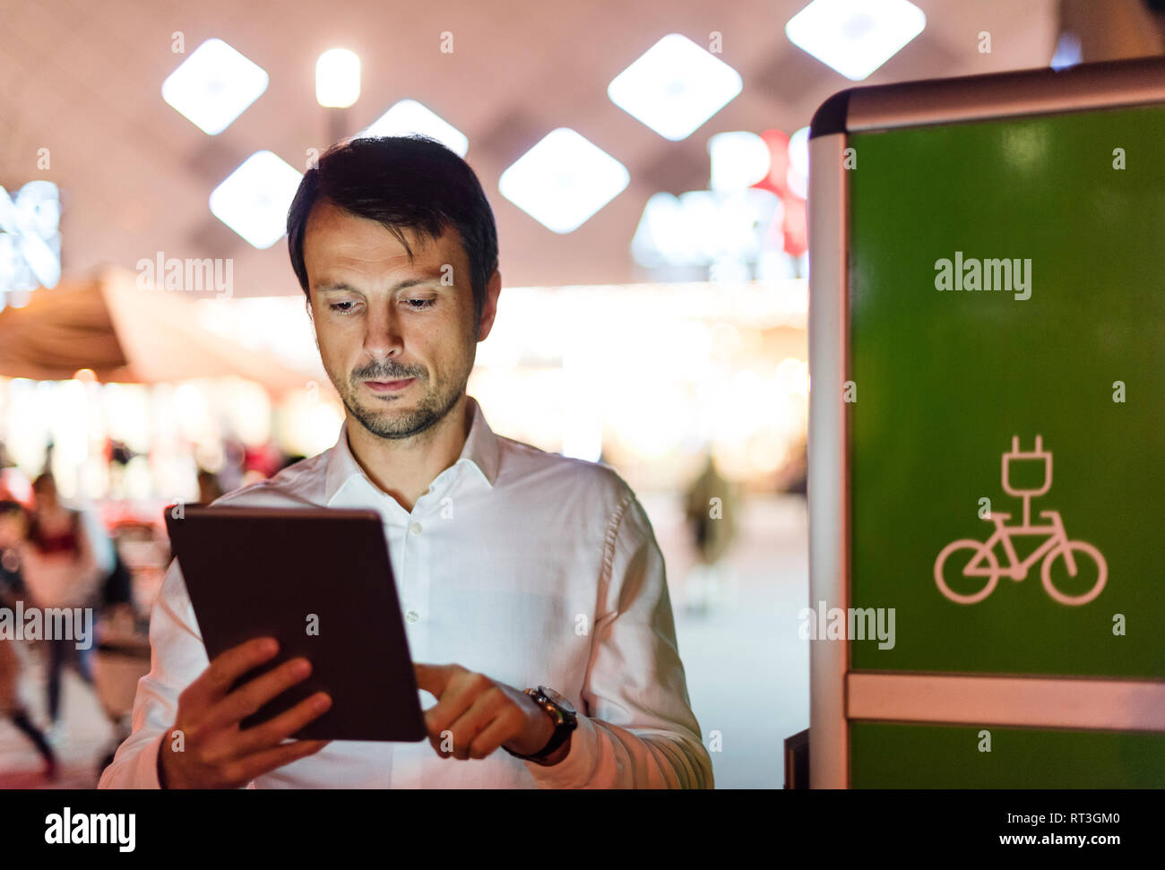 Imprenditore con tavoletta digitale accanto alla stazione di carica Foto Stock