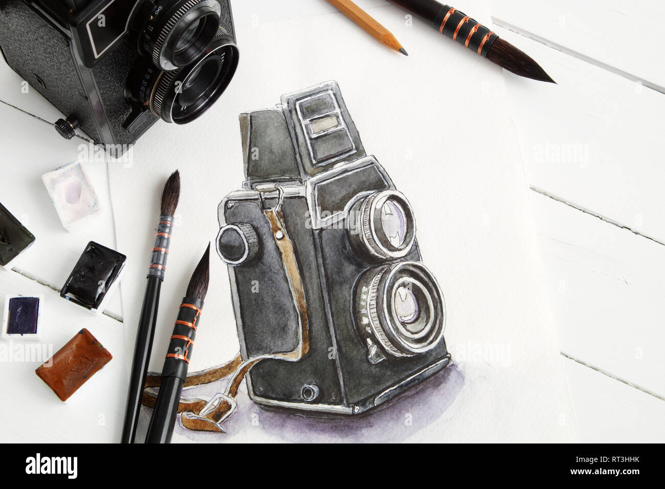 Disegno ad acquerello di fotocamera retrò, vintage fotocamera, pennelli e vernici ad acquerello. Appartamento laico, vista dall'alto. Foto Stock