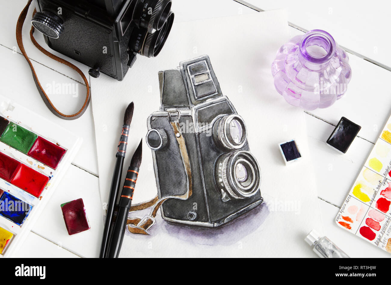 Disegno ad acquerello di fotocamera retrò, vecchia foto fotocamera, pennelli e vernici ad acquerello. Appartamento laico, vista dall'alto. Foto Stock