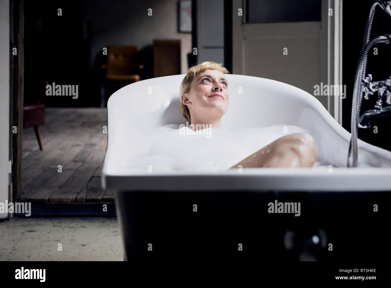 Ritratto di donna felice tenendo bagno di bolle in un loft Foto Stock