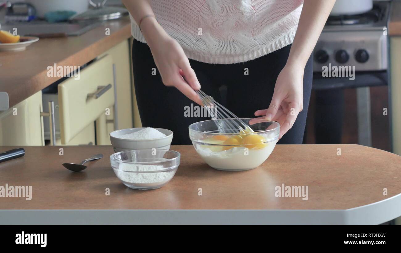 Panna i tuorli con lo zucchero in un recipiente di vetro bianco dell'uovo sbattuto viene miscelata con il tuorlo d'uovo crema di farina e di essere aggiunto Foto Stock