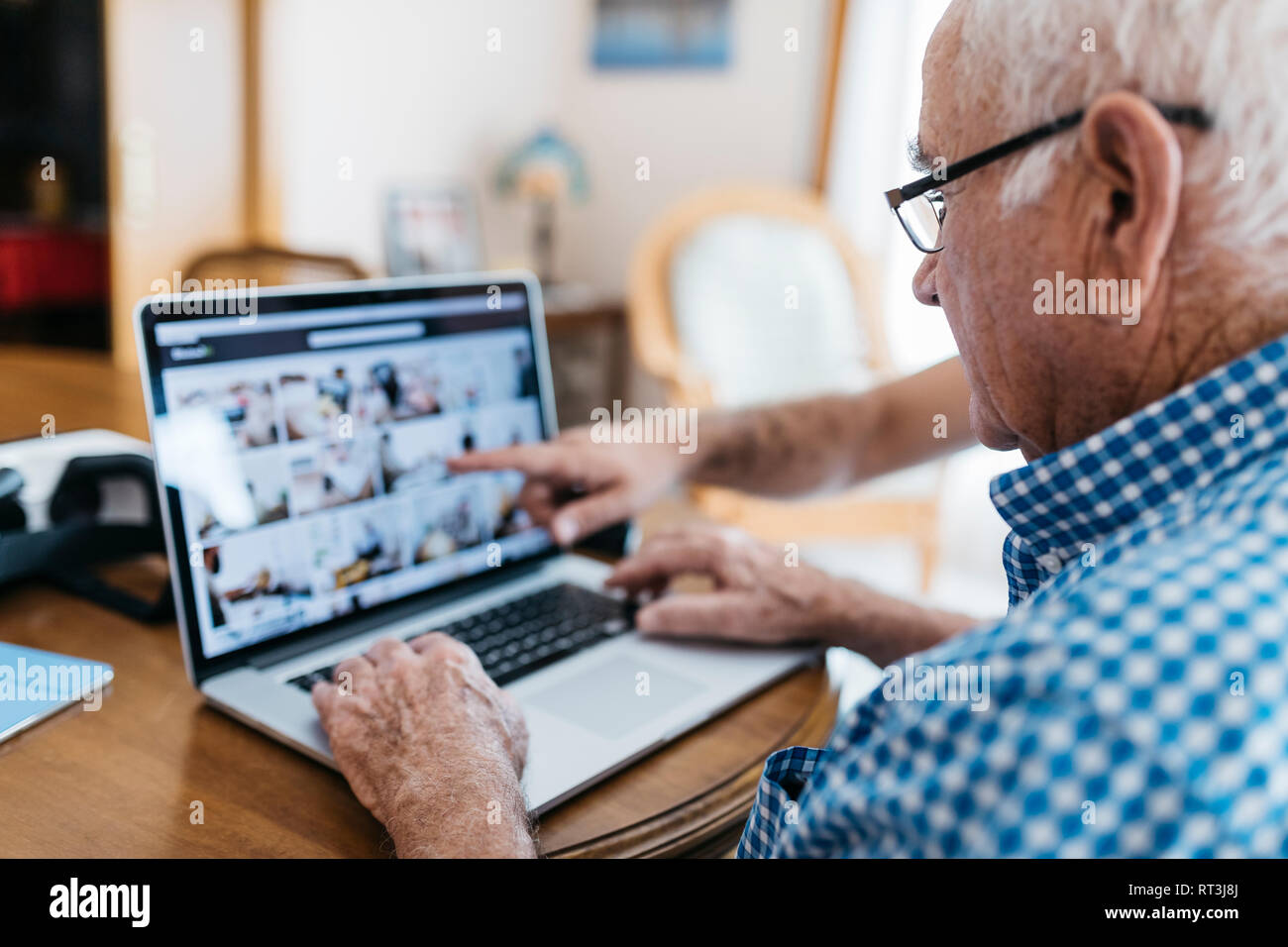 Nipote di adulti insegnamento a suo nonno per uso portatile Foto Stock