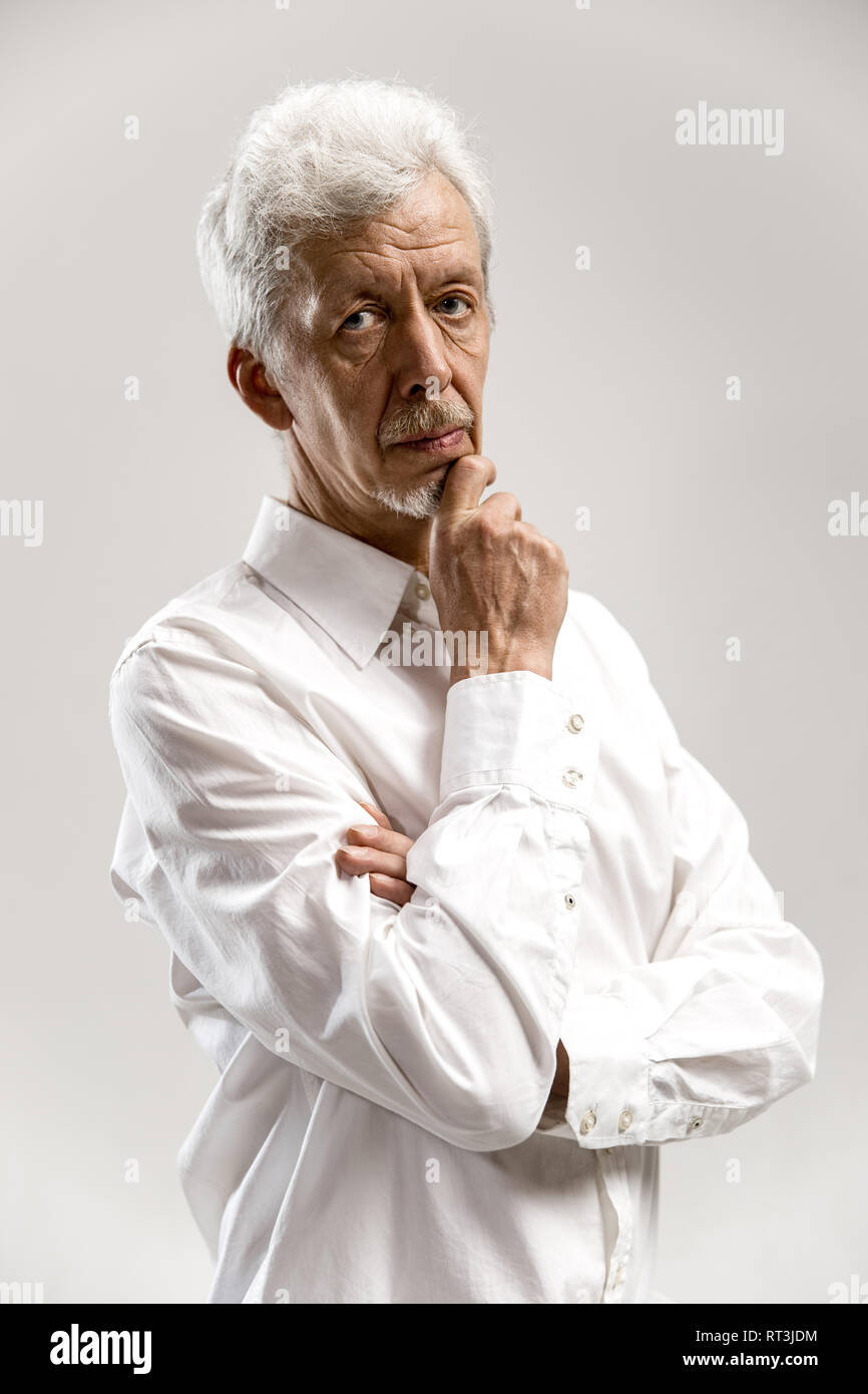 Imprenditore gravi isolato su grigio di sfondo per studio. Metà maschio-lunghezza verticale. Le emozioni umane, espressione facciale concept Foto Stock