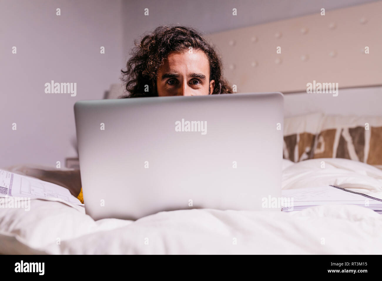 Ritratto di giovane uomo nel letto di casa utilizzando laptop Foto Stock