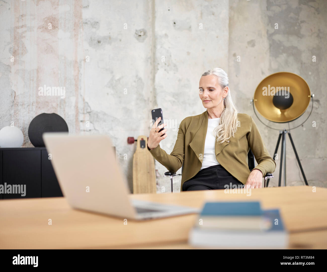 Imprenditrice guardando il cellulare in ufficio Foto Stock