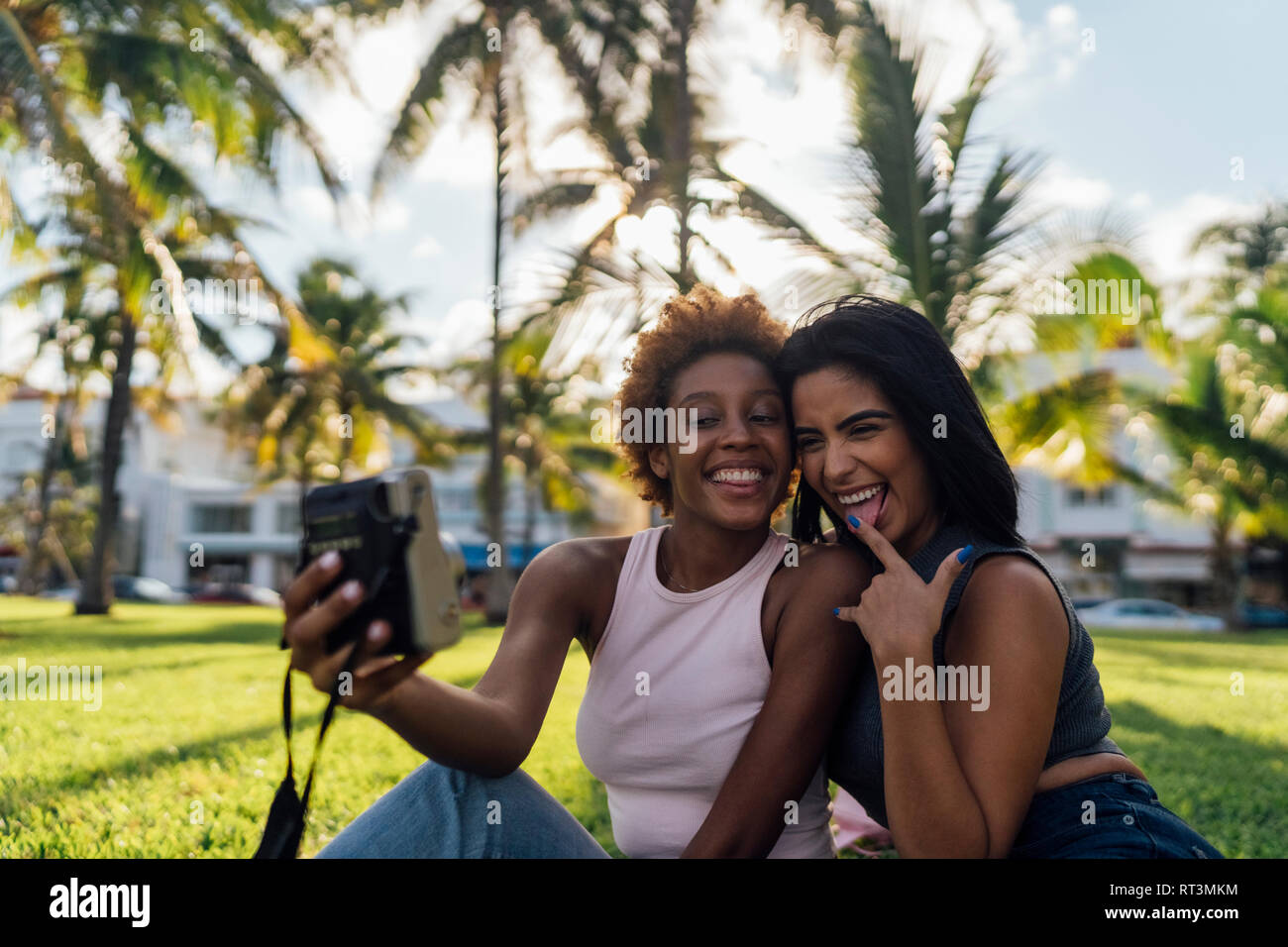 Due happy amici di sesso femminile prendendo una foto istantanea in un parco Foto Stock