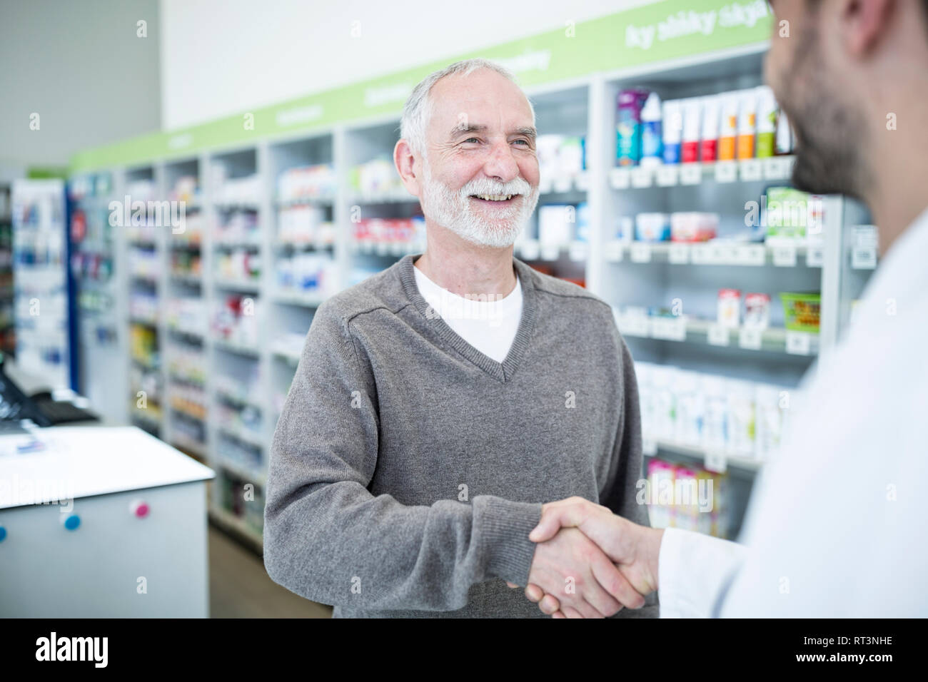 Il farmacista e il cliente si stringono la mano in farmacia Foto Stock