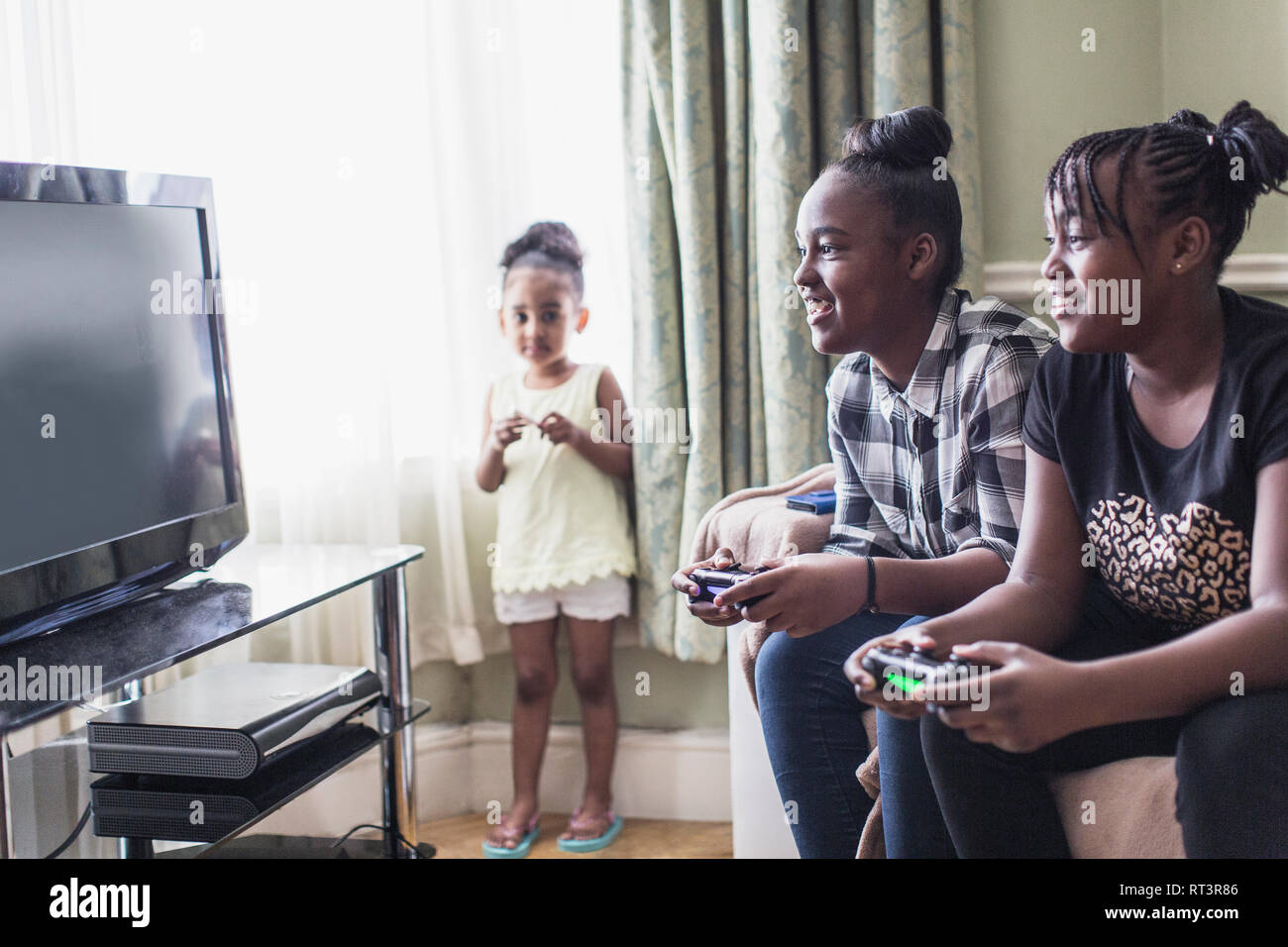 Il Toddler girl guardando tween sorelle la riproduzione del video gioco in soggiorno Foto Stock